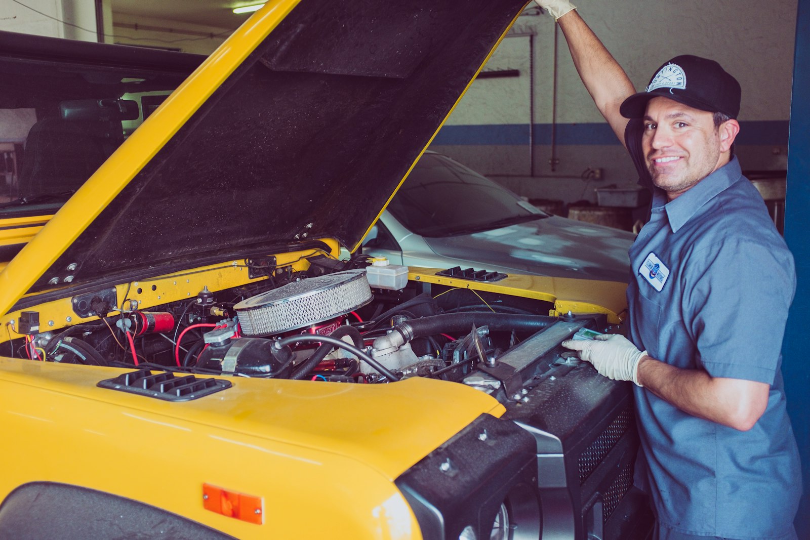 Friendly technician standing beside a vehicle with the hood raised